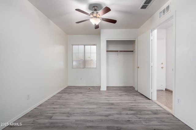 unfurnished bedroom featuring ceiling fan, light hardwood / wood-style floors, and a closet