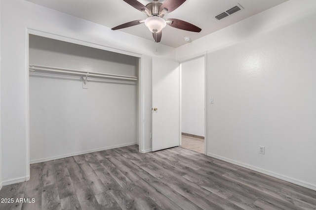 unfurnished bedroom with ceiling fan, wood-type flooring, and a closet