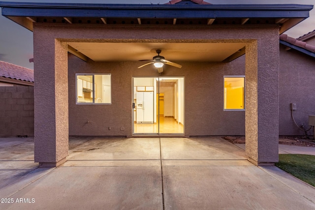 back house at dusk with a patio area and ceiling fan