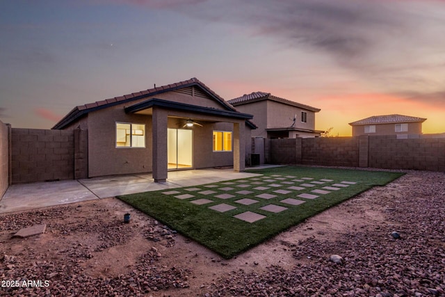 back house at dusk featuring a patio and ceiling fan