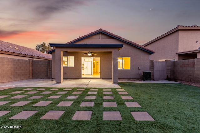 back house at dusk featuring a patio, a yard, central AC, and ceiling fan