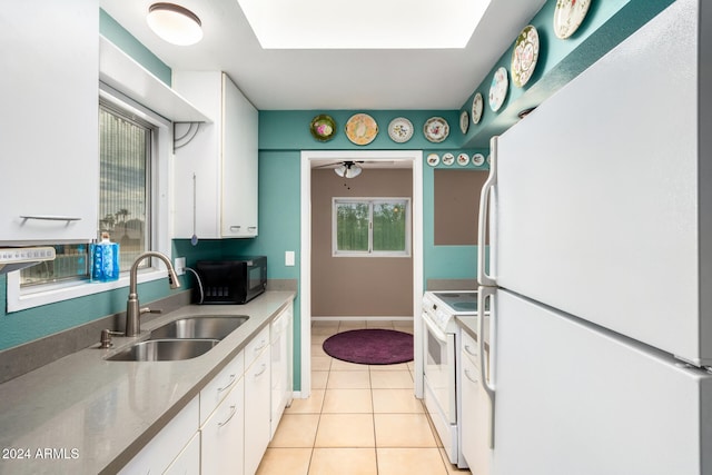 kitchen featuring a skylight, sink, white cabinets, and white appliances