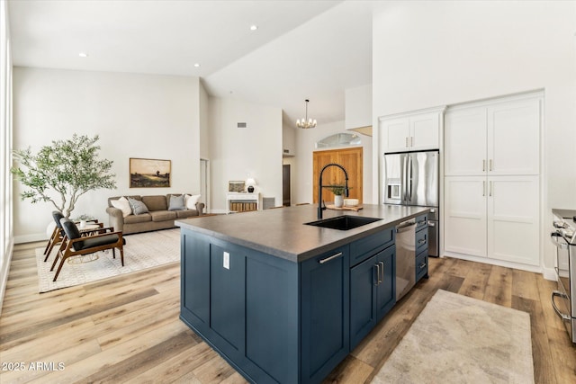 kitchen featuring sink, blue cabinetry, appliances with stainless steel finishes, white cabinetry, and an island with sink