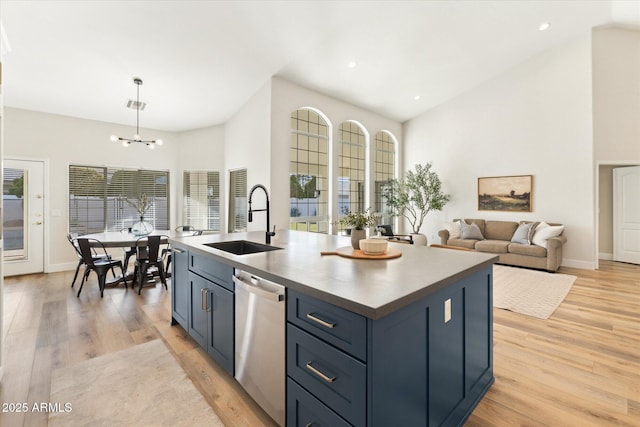 kitchen with sink, stainless steel dishwasher, an island with sink, and blue cabinets