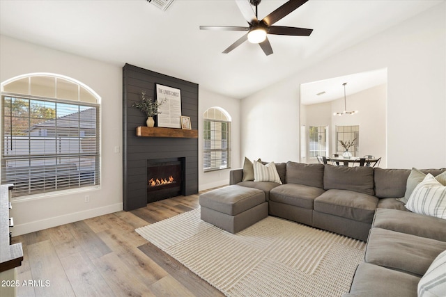 living room with ceiling fan, lofted ceiling, a fireplace, and light hardwood / wood-style floors