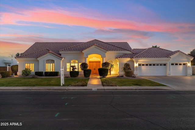 mediterranean / spanish home featuring a garage and a lawn