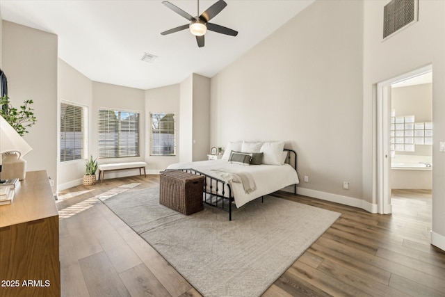 bedroom with ceiling fan, ensuite bath, high vaulted ceiling, and hardwood / wood-style floors