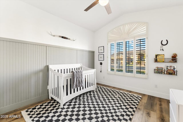 bedroom featuring a crib, vaulted ceiling, dark hardwood / wood-style floors, and ceiling fan