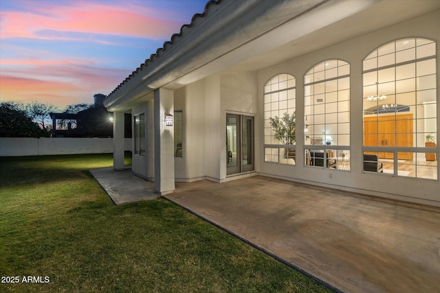 exterior entry at dusk with a yard and a patio area