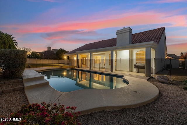 pool at dusk with a patio area