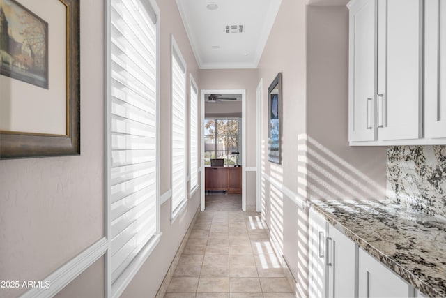 corridor featuring light tile patterned floors and crown molding