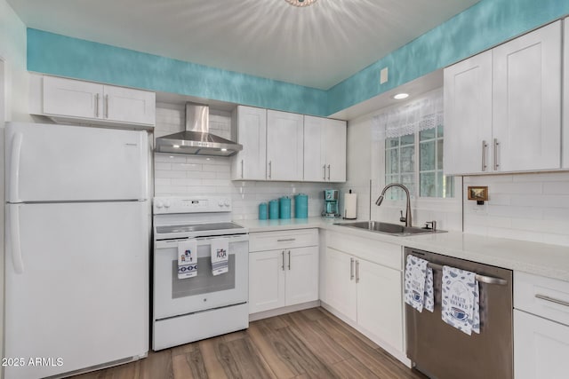 kitchen featuring sink, wall chimney range hood, backsplash, white appliances, and white cabinets