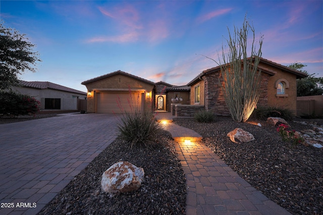 19334 W Pasadena Ave, Litchfield Park, AZ 85340 - view of front of property featuring a garage, decorative driveway, stucco siding, stone siding, and a tiled roof