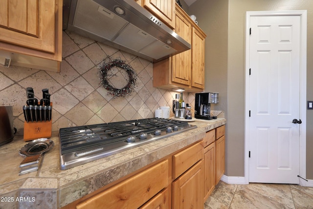 19334 W Pasadena Ave, Litchfield Park, AZ 85340 - kitchen featuring under cabinet range hood, stainless steel gas stovetop, backsplash, light countertops, and baseboards