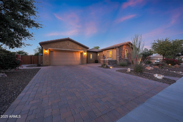 19334 W Pasadena Ave, Litchfield Park, AZ 85340 - view of front of home featuring a garage, fence, decorative driveway, stone siding, and a tile roof