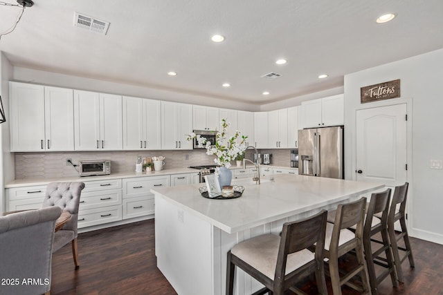 1342 E Jade Dr, Chandler, AZ 85286 - kitchen featuring stainless steel appliances, dark wood-style flooring, a kitchen bar, white cabinetry, and recessed lighting