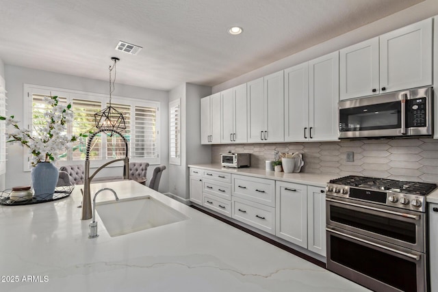 1342 E Jade Dr, Chandler, AZ 85286 - kitchen featuring appliances with stainless steel finishes, tasteful backsplash, decorative light fixtures, white cabinetry, and light stone countertops