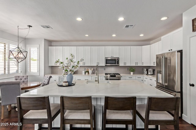 1342 E Jade Dr, Chandler, AZ 85286 - kitchen with high quality appliances, recessed lighting, white cabinets, a kitchen island with sink, and a kitchen breakfast bar