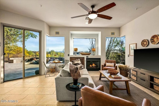 sunroom / solarium featuring ceiling fan and a glass covered fireplace