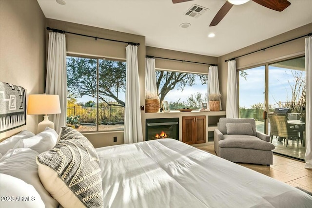 bedroom with visible vents, a ceiling fan, a glass covered fireplace, access to exterior, and tile patterned flooring