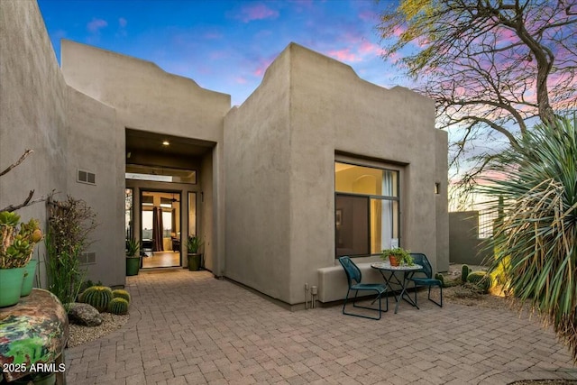 exterior space featuring a patio area, visible vents, and stucco siding