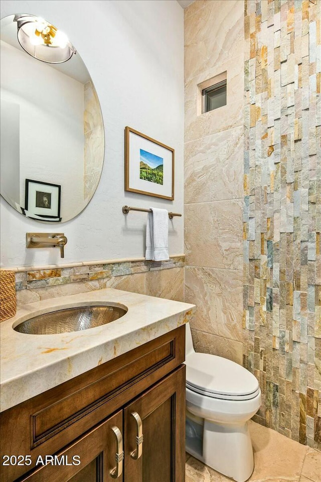 half bath featuring toilet, tile walls, and vanity