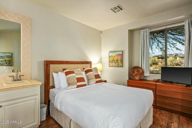 bedroom featuring visible vents, dark wood-type flooring, and a sink