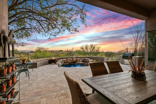 patio terrace at dusk featuring outdoor dining area, area for grilling, and fence