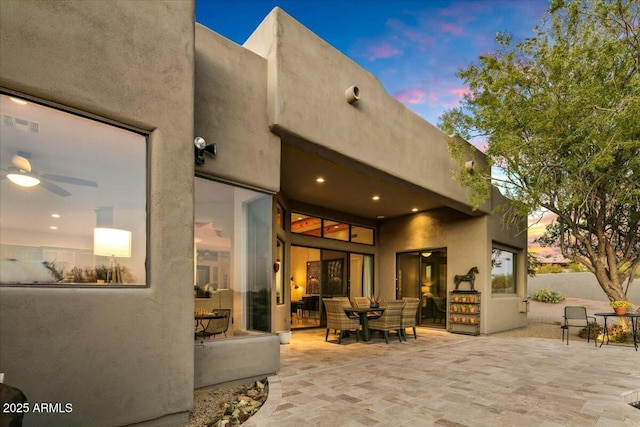 back of property at dusk featuring visible vents, a patio, and stucco siding