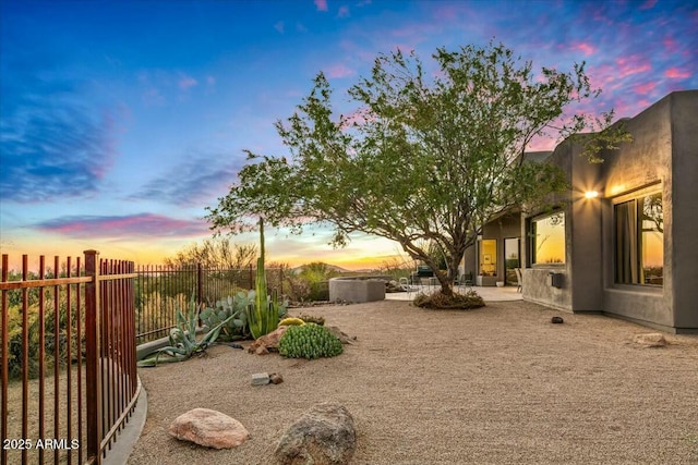 yard at dusk featuring a patio area and fence