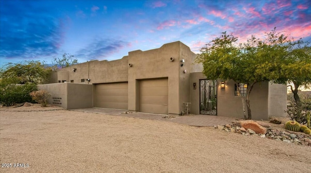 view of front of house featuring an attached garage, driveway, fence, and stucco siding