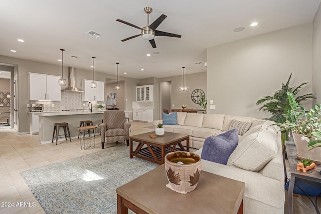 living room with ceiling fan, sink, and light tile patterned floors