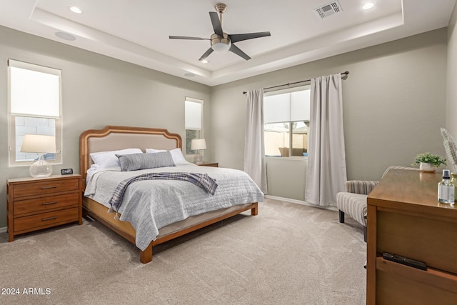 carpeted bedroom with ceiling fan and a tray ceiling