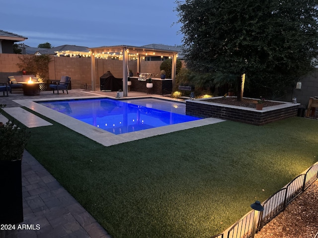 pool at dusk with a fire pit, an outdoor kitchen, and a patio