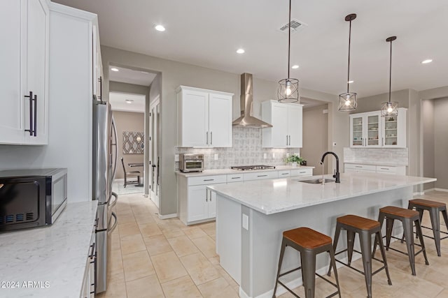 kitchen with white cabinetry, sink, and wall chimney range hood