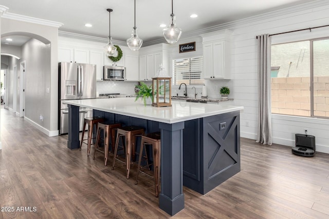 6317 S Banning St, Gilbert, AZ 85298 - kitchen with stainless steel appliances, arched walkways, white cabinetry, a large island, and ornamental molding