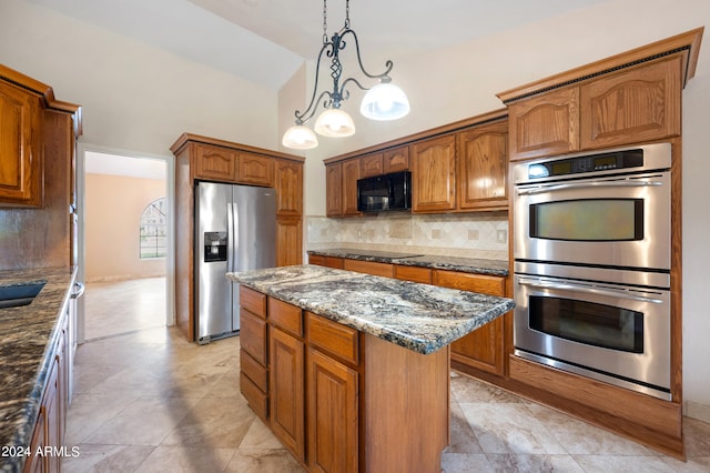 kitchen with dark stone countertops, black appliances, a kitchen island, and hanging light fixtures