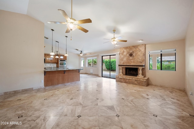 unfurnished living room featuring ceiling fan, a large fireplace, and vaulted ceiling