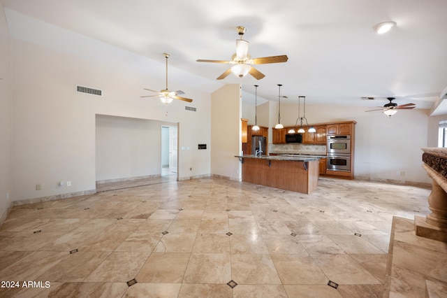 kitchen featuring hanging light fixtures, backsplash, appliances with stainless steel finishes, high vaulted ceiling, and stone counters