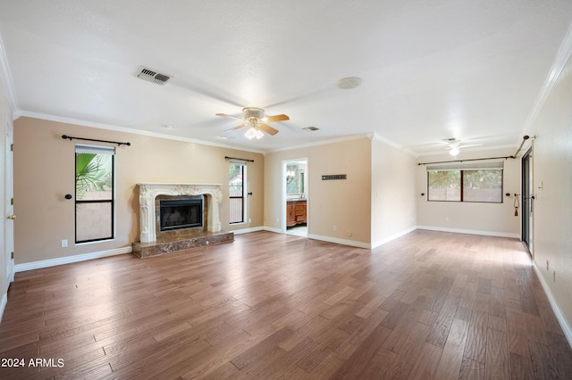 unfurnished living room featuring crown molding, hardwood / wood-style flooring, a fireplace, and a wealth of natural light