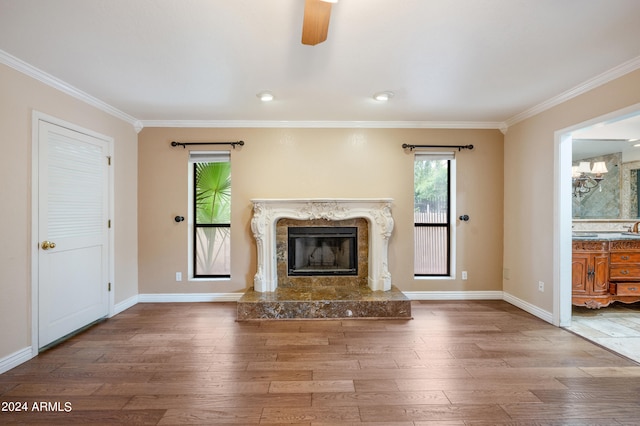 unfurnished living room featuring a premium fireplace, crown molding, hardwood / wood-style flooring, and ceiling fan