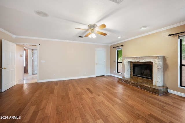 unfurnished living room with crown molding, ceiling fan, light wood-type flooring, and a wealth of natural light