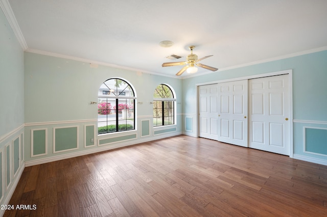 unfurnished bedroom with a closet, crown molding, hardwood / wood-style flooring, and ceiling fan