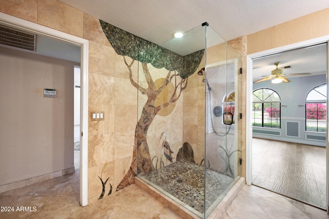 bathroom with ceiling fan, hardwood / wood-style flooring, a textured ceiling, and tiled shower