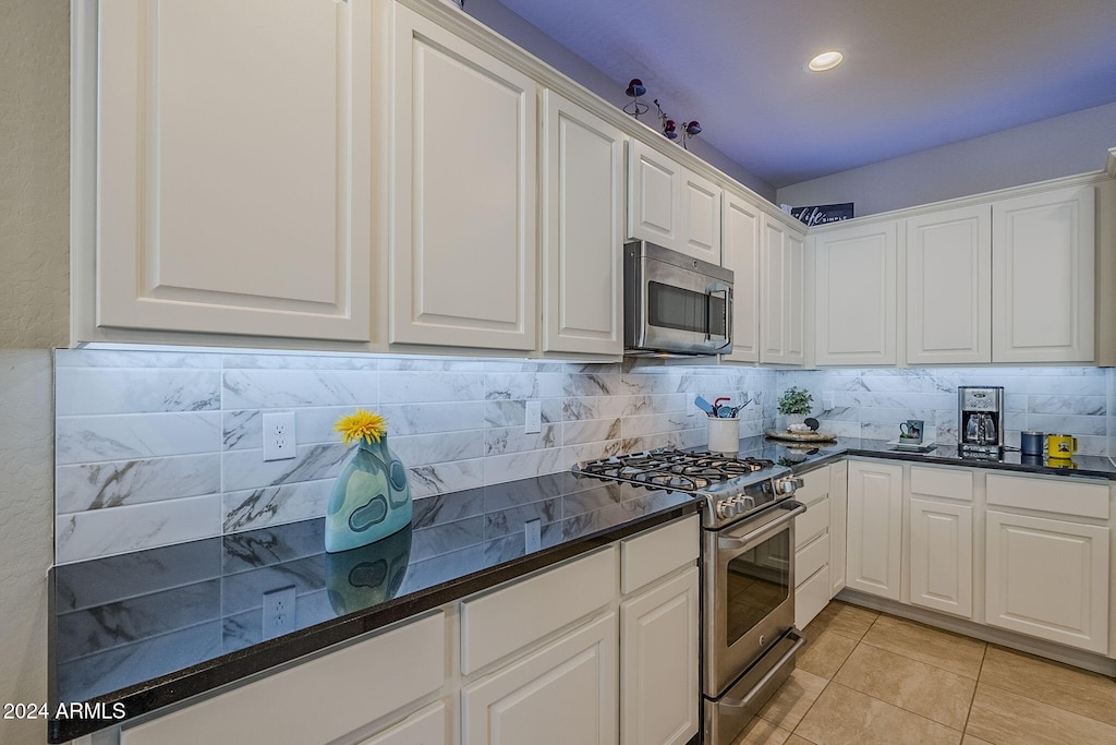 kitchen featuring stainless steel appliances, light tile patterned floors, white cabinets, and decorative backsplash