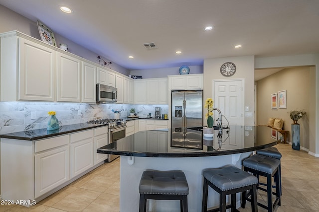 kitchen featuring sink, stainless steel appliances, a kitchen breakfast bar, white cabinets, and a center island with sink