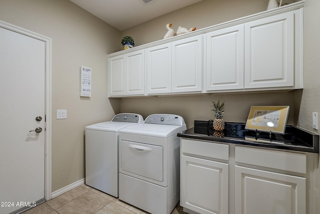 laundry room with light tile patterned floors, washer and clothes dryer, and cabinets