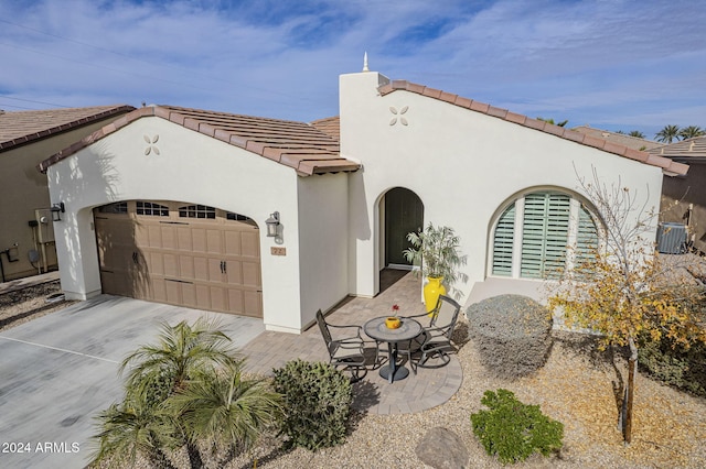 view of front of house with cooling unit, a garage, and a patio