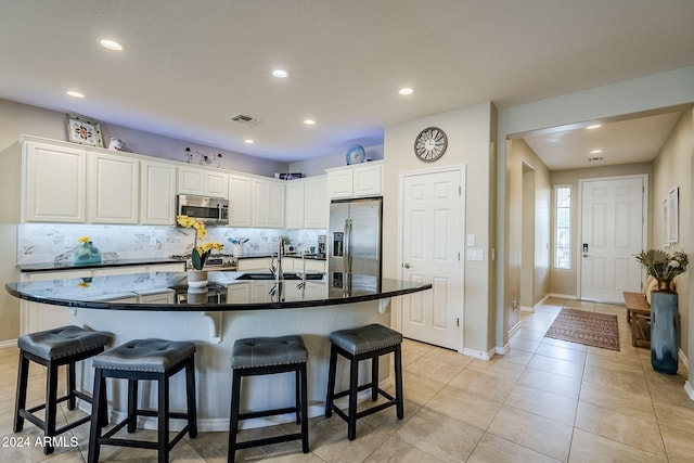 kitchen with a kitchen bar, sink, backsplash, appliances with stainless steel finishes, and white cabinets