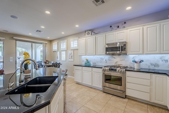 kitchen featuring sink, white cabinetry, light tile patterned floors, appliances with stainless steel finishes, and backsplash